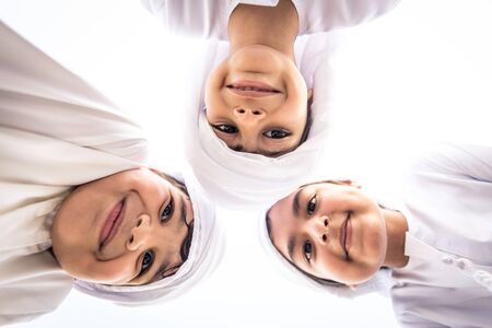Group of middle-eastern kids wearing white kandora playing in a park in Dubai - Happy group of friends having fun outdoors in the UAEの写真素材
