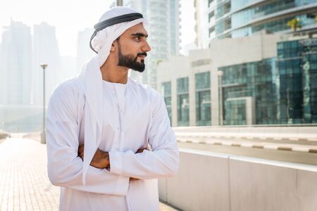 Middle-eastern young adult wearing kandora walking outdoors in Dubai - Arabic man wearing the...