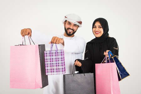 Middle-eastern family with traditional emirates clothes holding shopping bagsの写真素材