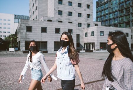 Group of asian girls going out after quarantine during coronavirus period. Young women outdoor with safety masksの写真素材