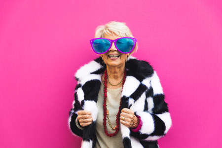 Happy and playful senior woman having fun - Portrait of a beautiful lady above 70 years old with stylish clothes, concepts about senior peopleの写真素材