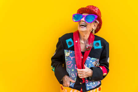 Happy and playful senior woman having fun - Portrait of a beautiful lady above 70 years old with stylish clothes, concepts about senior peopleの写真素材