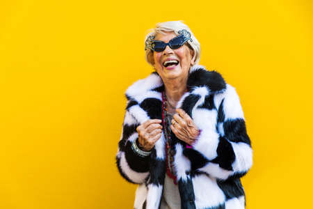 Happy and playful senior woman having fun - Portrait of a beautiful lady above 70 years old with stylish clothes, concepts about senior peopleの写真素材