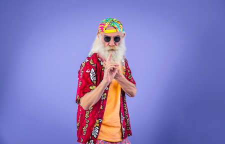 Fashionable grandfather posing with funny clothes. Senior man portraits on colored backgroundの写真素材