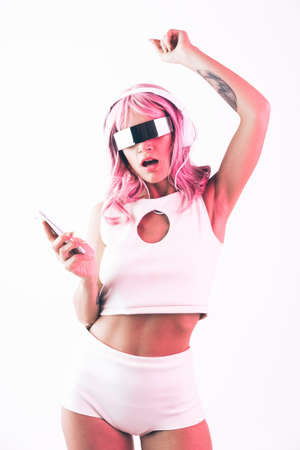 Young woman with pink hair dancing and having fun. Colored gel portraits with futuristic outfitの写真素材