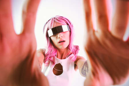 Young woman with pink hair dancing and having fun. Colored gel portraits with futuristic outfit