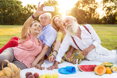Group of seniors making a picnic at the park and having fun.の写真素材