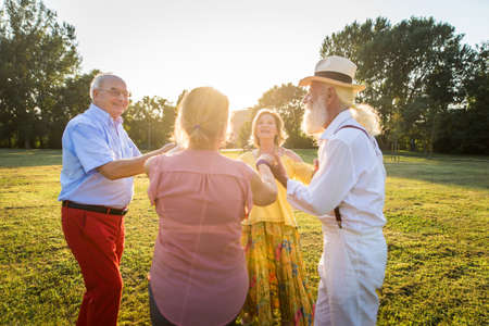 Group of youthful seniors having fun outdoors - Four pensioners bonding outdoors, concepts about lifestyle and elderlyの写真素材