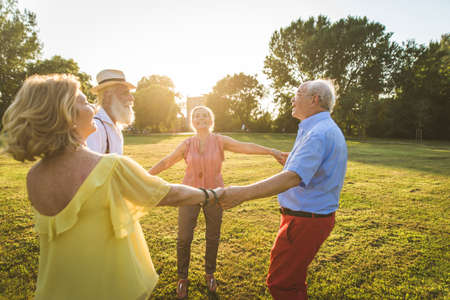 Group of youthful seniors having fun outdoors - Four pensioners bonding outdoors, concepts about...