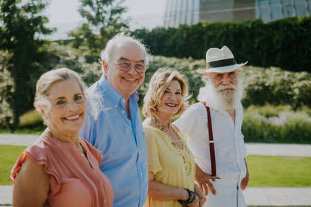Group of youthful seniors having fun outdoors - Four pensioners bonding outdoors, concepts about...