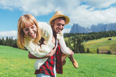Happy couple on vacation on the italian dolomites mountains. Young man and woman playing together on...