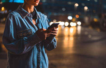 Image of a young woman using mobile phone on the street. Girl with short shaved hair walking in the...