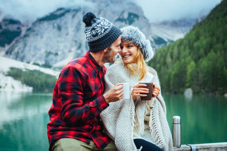 Beautiful couple of young adults visiting an alpine lake at Braies, Italy - Tourists with hiking outfit having fun on vacation during autumn foliage - Concepts about travel, lifestyle and wanderlustの写真素材