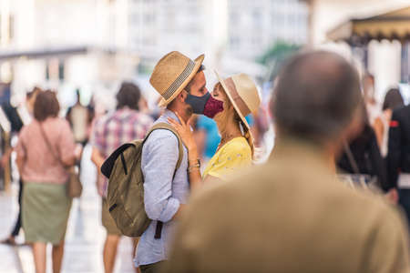 Beautiful couple wearing protective face masks and kissing during covid-19 pandemic, concepts about lifestyle, epidemic era and social distancingの写真素材