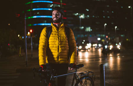 Food delivery rider on his bicycle. Image of a middle age man at work in the city center. Delivering pizza and burgers at home with the thermal backpackの写真素材