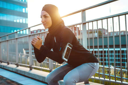 Muslim urban runner training in the city center. Beautiful woman doing sport in the early morning