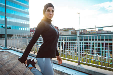 Muslim urban runner training in the city center. Beautiful woman doing sport in the early morning