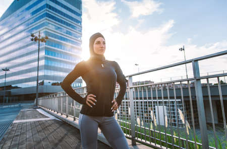 Muslim urban runner training in the city center. Beautiful woman doing sport in the early morningの写真素材
