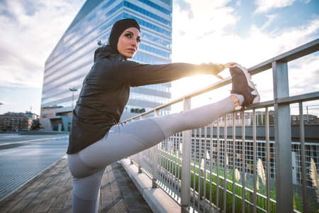 Muslim urban runner training in the city center. Beautiful woman doing sport in the early morningの写真素材