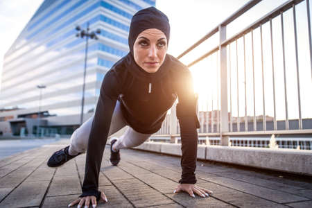 Muslim urban runner training in the city center. Beautiful woman doing sport in the early morning