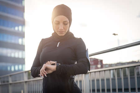 Muslim urban runner training in the city center. Beautiful woman doing sport in the early morning
