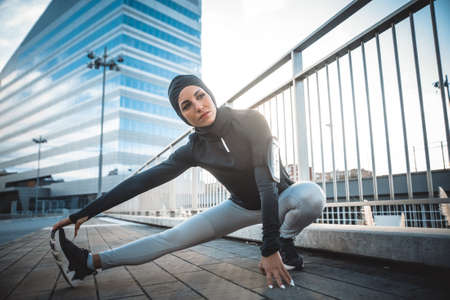Muslim urban runner training in the city center. Beautiful woman doing sport in the early morningの写真素材