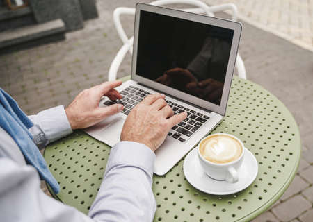 Cheerful senior man portrait - Mature adult using his computer laptop in a bar coffeehouse, concepts...