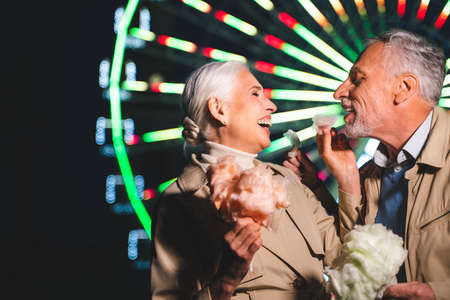 Beautiful senior couple dating outdoors - Mature couple having fun at amusement park, concepts about elderly and lifestyleの写真素材
