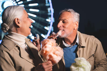 Beautiful senior couple dating outdoors - Mature couple having fun at amusement park, concepts about elderly and lifestyleの写真素材