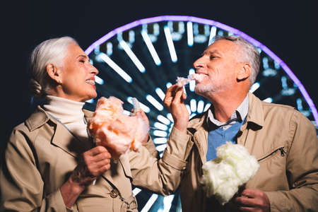Beautiful senior couple dating outdoors - Mature couple having fun at amusement park, concepts about elderly and lifestyleの写真素材
