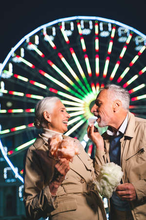 Beautiful senior couple dating outdoors - Mature couple having fun at amusement park, concepts about elderly and lifestyleの写真素材