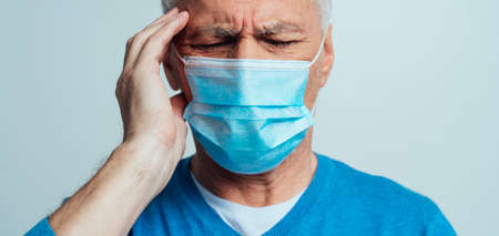 Handsome senior isolated on gray background. Old man wearing the medical mask. Concept about the...