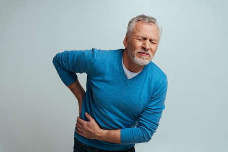 Handsome senior isolated on gray background. Old man feeling pain. Concept about the third age and...