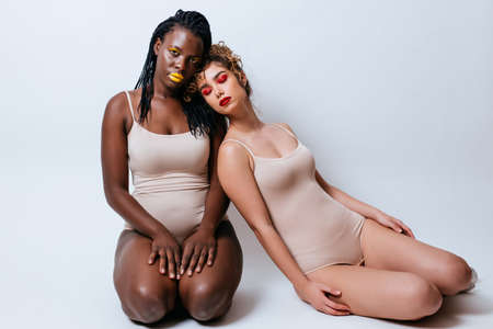 Two girls from different ethnicities posing in the studio for a "body positivity" photo sessionの写真素材