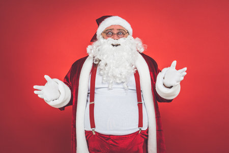 Funny crazy santa claus having fun on a red colored backgroundの写真素材