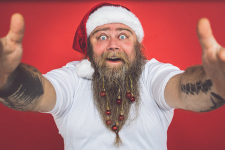 Funny crazy santa claus with tattoo having fun on a red colored backgroundの写真素材