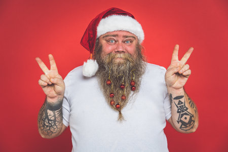 Funny crazy santa claus with tattoo having fun on a red colored backgroundの写真素材