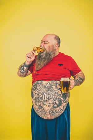 Man watching television while drinking and eating. Funny hipster man portrait on a colored backgroundの写真素材