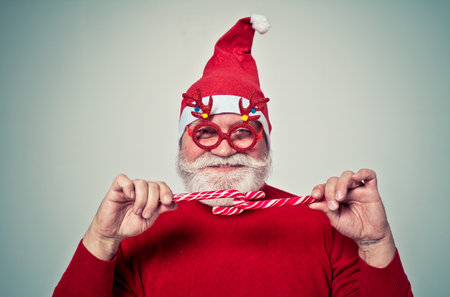 Funny senior man posing as santa claus in a photo shooting. Happy hipster doing funny expressions. Concept about people and christmasの写真素材