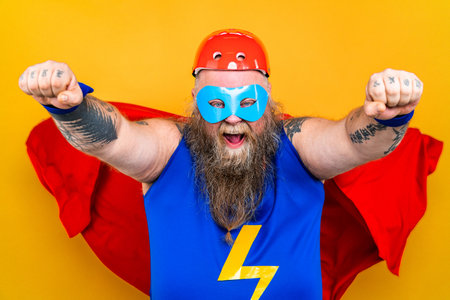 Funny fat man with superhero costume acting as superhuman with special powers, portrait on colored...