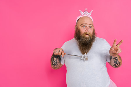 Funny fat man pretending to be a ballerina with tutu - Comic character with beard and tattooes dancing on a pink backgroundの写真素材