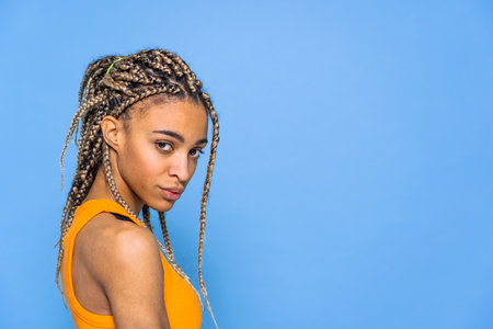 Beautiful afroamerican woman with pigtails portrait on colored backgroundの写真素材