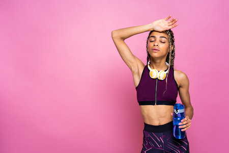 Beautiful afroamerican woman with pigtails portrait on colored background doing sport exercises -...