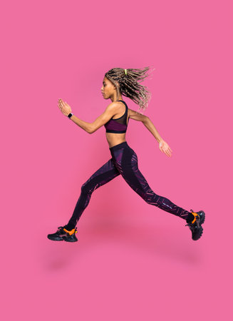 Beautiful afroamerican woman with pigtails portrait on colored background doing sport exercises -...