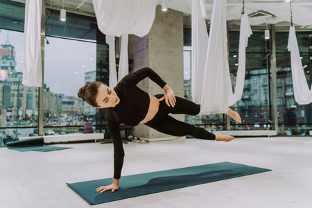 Beautiful athletic woman training in a gym, doing stretching exercises before the workout - Pretty...