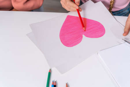 Beautiful cute girl at elementary school doing homeworks at home - Mom helping daughter to studyの写真素材