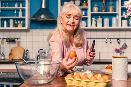 Beautiful senior woman baking in the kitchen - Grandmother preparing desserts at home, concepts about baking, cooking and healthy eatingの写真素材