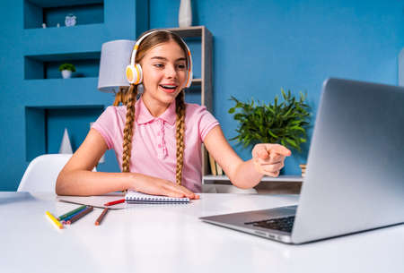 Beautiful cute girl at elementary school doing homeworks at home - Child in young age remote learning at home during coronavirus pandemic quarantineの写真素材