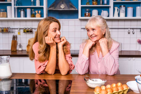 Beautiful senior woman and daughter baking in the kitchen - Grandmother preparing desserts at home...