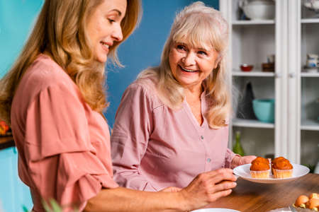Beautiful senior woman and daughter baking in the kitchen - Grandmother preparing desserts at home with family, concepts about cooking and healthy eatingの写真素材